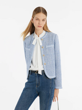 a lady in a light blue round neck crop jacket with skinny jeans